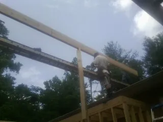 Carpenter setting a ridge beam over a new addition frame — Ice Dam Removal by Roofing Brothers in Clatonia