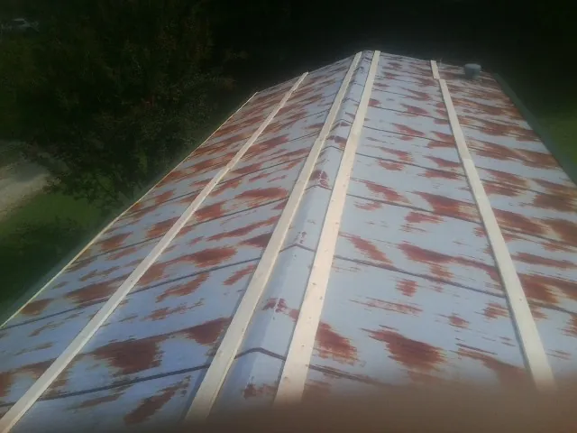 Rusted metal roof panels with new wood purlins before replacement — Storm Damage Roof Repair in Clatonia by Roofing Brothers
