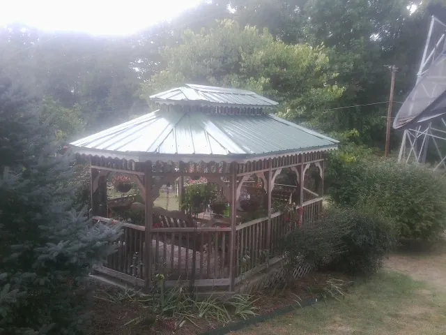 Green metal roof on a backyard gazebo surrounded by garden beds in Clatonia