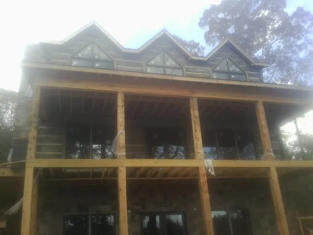 Dormers and porch framing on a large log home under construction — Roof Coating work by our crew in Clatonia