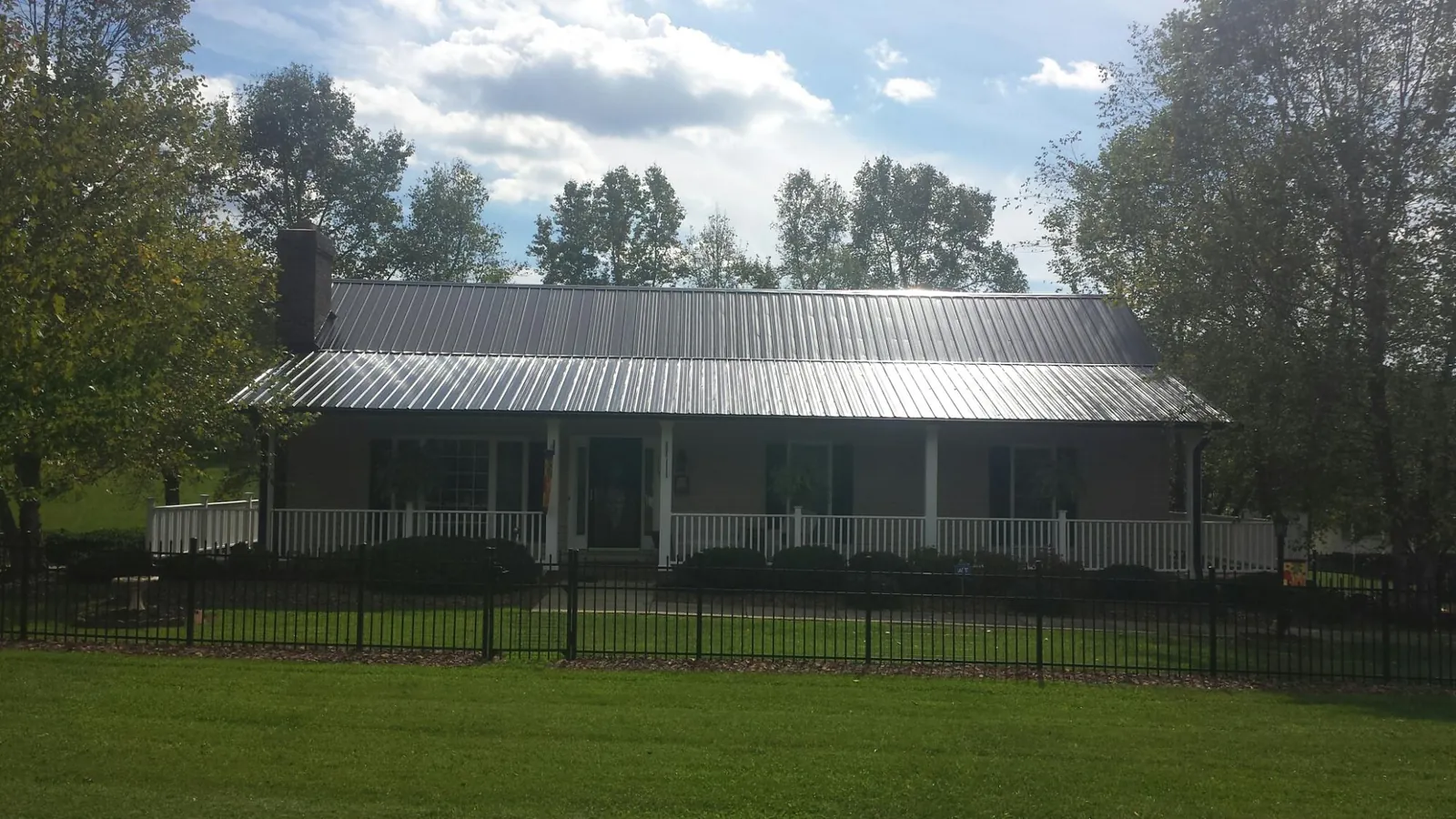 Gray metal roof on a brick ranch with a full width front porch — Gutter Guard Installation work by our crew in Clatonia