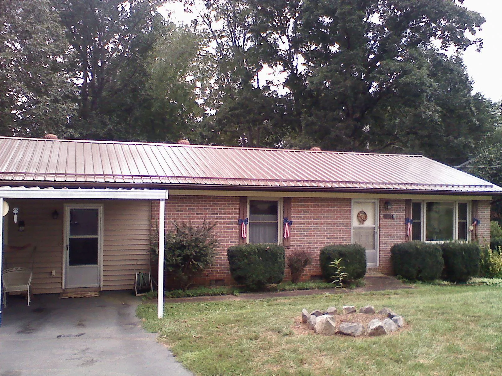 Bronze metal roof and carport on a brick ranch home — Roof Repair work by our crew in Clatonia