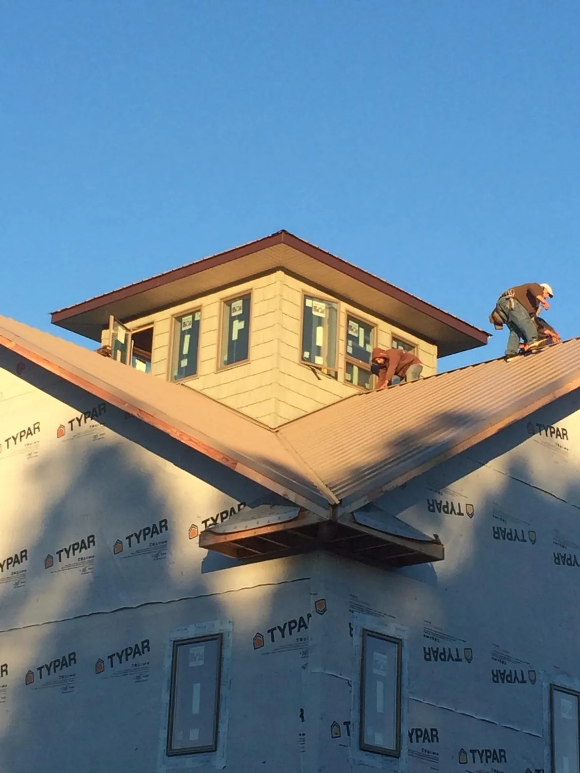 Roofers working around a rooftop cupola on a new metal roof at sunset — Roof Waterproofing in Clatonia by Roofing Brothers